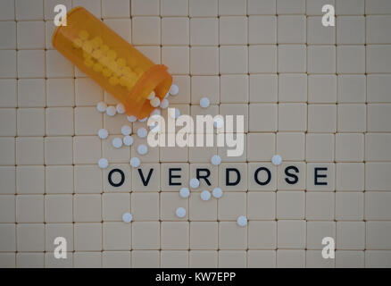 Tan tiles with black capital letters spelling overdose set in a background of small tan tiles. An open orange prescription bottle with oxycodone pills Stock Photo