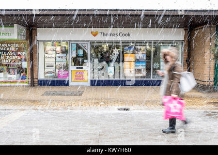 Woman walks past exterior of branch of  Thomas Cook Travel Agency in winter snow Stock Photo