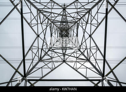 Abstract pattern looking directly up underneath high electricity pylon against a cloudy sky, Scotland, UK Stock Photo