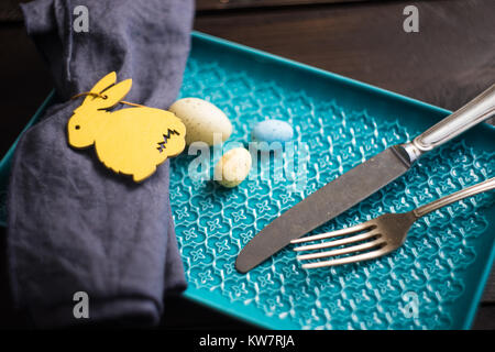 Table setting for festive Easter dinner decorated with easter bunny and eggs on dark wooden table Stock Photo