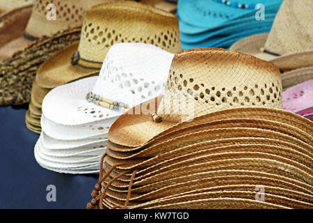 Cowboy Hats For Sale - Straw hats of various colors and designs lined up on Vendor table Stock Photo