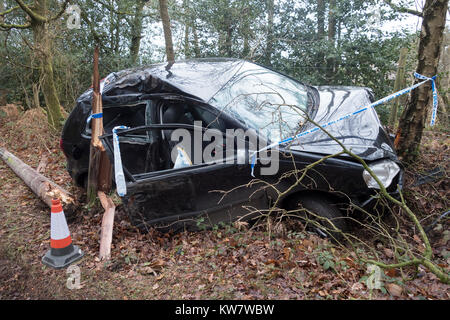 A crashed car, a black Volkswagen Polo, in a country lane surrounded by Police tape having left the road and hit a tree Stock Photo
