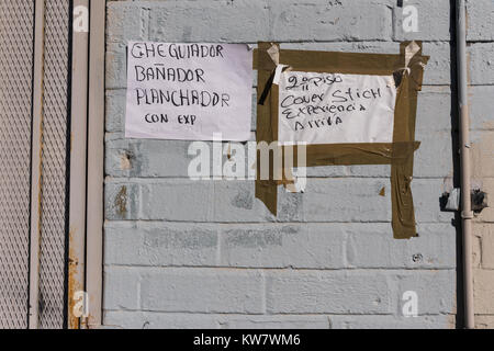 Help wanted signs in Spanish and English, taped to an exterior wall in the Fashion District of Downtown Los Angeles, California. Stock Photo