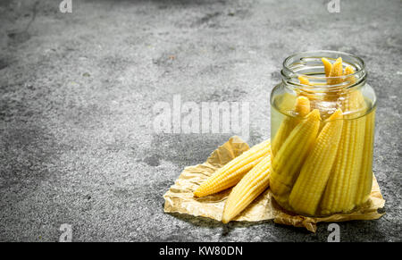 Marinated corn in glass jar. On a rustic background. Stock Photo