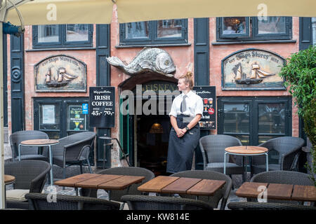Waitress outside a waterfront restaurant at Nyhavn, a 17th century harbor district in the center of Copenhagen and a popular tourist attraction Stock Photo