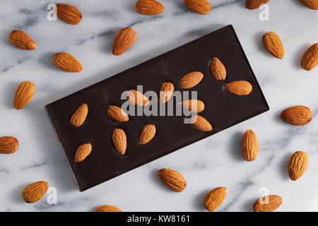 Top view of the dark chocolate with almonds on a white marble background Stock Photo