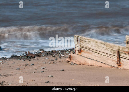 The incoming tide and waves having their energy dissipated by the wooden breakwaters on the sandy and pebbled beach at the seaside resort of Cleveleys Stock Photo