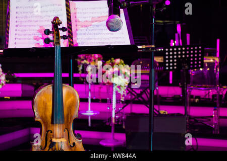 close up photo of vintage violin with microphone and musical notes in concert hall Stock Photo