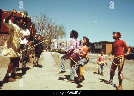 Several black children are playing jump rope outside of the Ida B Wells Homes, one of Chicago's oldest housing projects, Chicago, Illinois, 1973. Image courtesy John White/US National Archives. Image courtesy National Archives.