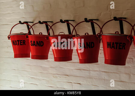 Row of red fire fighting buckets hung on a wall Stock Photo