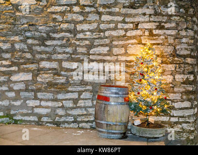 Old wooden barrel and illuminated christmas tree in front of limestone wall Stock Photo