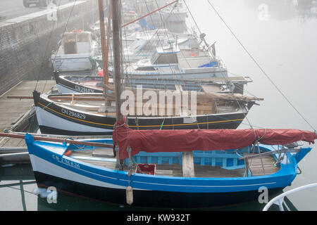 Misty morning in Port-en-Bessin, Normandy, with traditional French chaloupe sailing fishing boats moored in the harbour Stock Photo