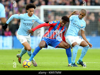 Crystal Palace's Wilfried Zaha battles for the ball with Manchester City's Leroy Sane and Fernandinho (right) during the Premier League match at Selhurst Park, London. Stock Photo