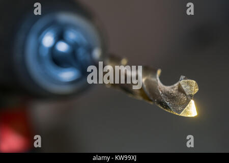 Steel drill HSS (High Speed Steel) in chuck of hand drill. Close-up of cutting tool tip with blurred background. Small depth of sharpness. Stock Photo