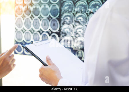 Professor Doctor discussion a method with patient treatment, with Mammogram film x-ray of patient 's head for brain, skull or eye injury and laptop co Stock Photo