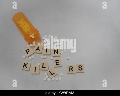 Pain Killer spelled with tile letters placed in haphazard fashion with an open bottle of oxycodone tablets. Photographed from above on stainless steel Stock Photo