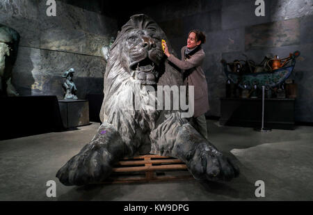 Kate Diment from Summers Place Auctions, polishes one of a pair of giant bronze lions in the style of those which famously guard Trafalgar Square, modelled on the originals designed by artist Sir Edwin Landseer which surround Nelson's Column, which could sell for up to £100,000 at auction, when they go under the hammer in Billingshurst, West Sussex, in March. Stock Photo