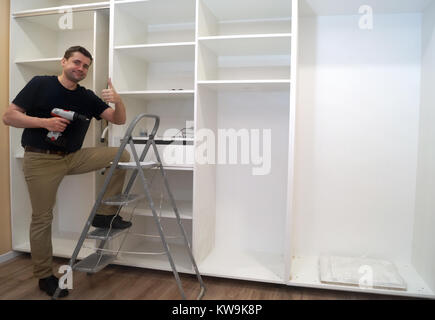 Smiling Service man at the time of assembling of built-in wardrobe. Stock Photo