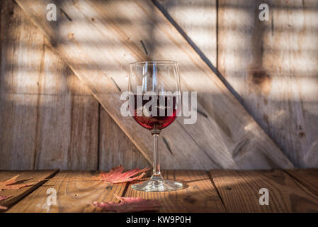 glass of red wine on rustic wood table and barn door Stock Photo