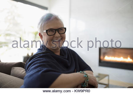 Portrait smiling,happy,confident senior woman on living room sofa near fireplace