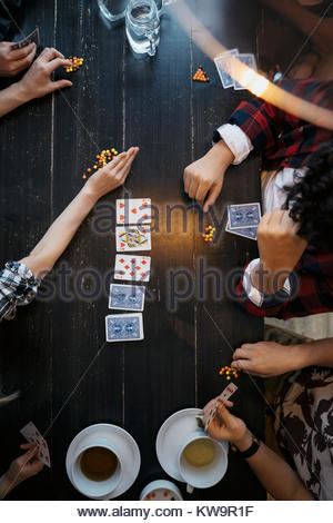 Overhead view tween friends playing cards with candy at table