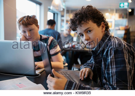Portrait serious,confident high school boy student studying at laptop in cafe