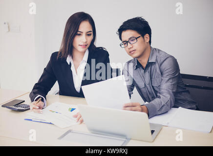 Asian businessmen and group using notebook for business partners discussing documents and ideas at meeting and business women smiling happy for workin Stock Photo