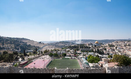 Panoramic view of Dome of the Rock shrine at the Old City of Jerusalem, surrounded by houses and other buildings, including a soccer field. Stock Photo