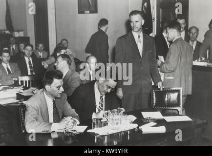 Paul Crouch (standing), an ex-Communist, testified against Clarence Hiskey (left). Hiskey was wartime atomic scientist, and an active member of the Communist Party in 1939-40. They are before the House Un-American Activities Committee in a face-to-face confrontation on May 24, 1949. In center, is Albert Collons, Hiskey's attorney. (BSLOC 2014 13 65) Stock Photo