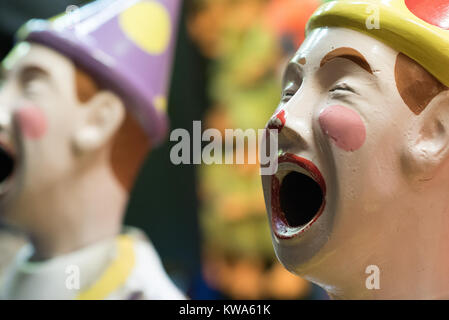 Brightly coloured laughing clowns at an amusement park. Stock Photo
