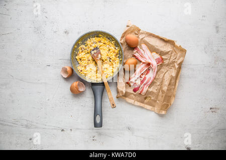 Ham and eggs. Scrambled eggs with bacon in ceramic pan. Stock Photo