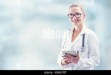 Young doctor woman smile face with tablet stethoscope and white coat. Stock Photo