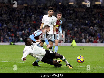 Liverpool's Sadio Mane goes down in the penalty area under a challenge from Burnley's Phil Bardsley (back) during the Premier League match at Turf Moor, Burnley. Stock Photo