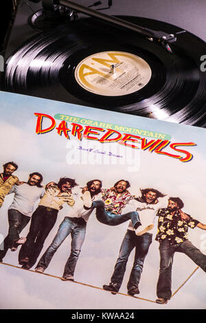 Vinyl record -The Ozark Mountain Daredevils 1977 LP on turntable / record player. Stylus playing track, label in view, album cover / sleeve alongside. Stock Photo