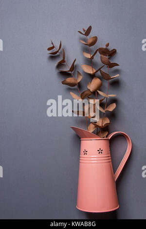 Bouquet of Dry Red Orange Silver Dollar Eucalyptus in Vintage Metal Pink Jug on Grey Background. Flat Lay Creative. Website Banner Template. Copy Spac Stock Photo