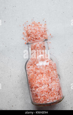 Pink Himalayan Salt in Vintage Glass Bottle Spilled on White Marble Stone Tabletop. Wellness Spa Healthy Diet Nutrition Ayurveda Concept. Clean Minima Stock Photo