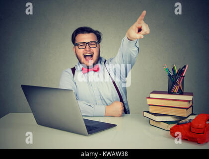 Young chubby man sitting at working desk and pointing away dismissing employee. Stock Photo