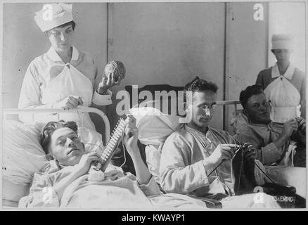 Three wounded soldiers knit from a hospital bed at Walter Reed Hospital, Washington, District of Columbia, 1917. Image courtesy National Archives. Stock Photo