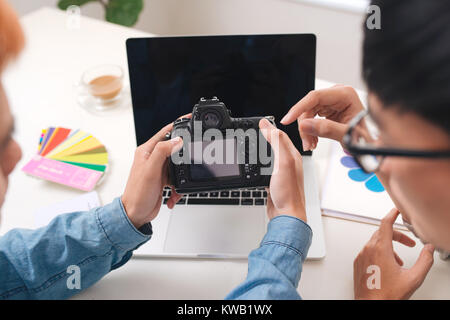 Photo editors looking at camera in studio sitting on the desk Stock Photo
