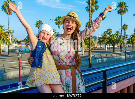 Summertime at colorful Barcelona. smiling elegant mother and daughter travellers on embankment in Barcelona, Spain rejoicing Stock Photo