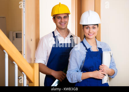 Young happy professionals team of builders watching the indoor site around. Focus on the woman Stock Photo
