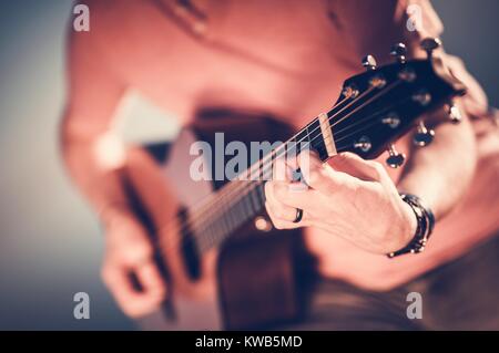 Caucasian Musician Playing Acoustic Guitar. Hand on Guitar Strings Closeup Photo. Music Performing. Stock Photo