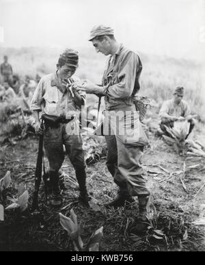 U.S. soldier of lights a cigarette for a former enemy guard. They are at a surrender conference between American and Japanese officers on a Sierra Madre mountain top in Northern Luzon, Philippines. Aug. 22, 1945. World War 2. (BSLOC 2014 10 128) Stock Photo
