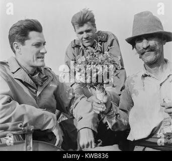 CBS News correspondent Eric Sevareid reporting from Italy during World War 2. He receives flowers from Italian peasant  on June 20, 1944. fellow journalist, Newbold Noyes, observe the event. (BSLOC 2014 8 214) Stock Photo