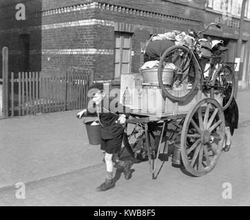 A boy pulls, as his mother pushes, a cart loaded with their possessions in Uerdingen, Germany. U.S. Army evacuated civilians from the city on the West bank of the Rhine on March 19, 1945. World War 2. (BSLOC 2014 8 85) Stock Photo