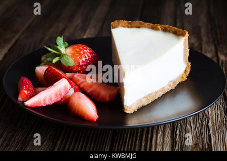 Plain New York Cheesecake with Fresh Strawberries on black plate. Closeup view, selective focus. Horizontal composition Stock Photo