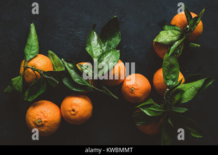 Tangerines or clementines with green leaf. Still life on dark background. Top view, toned image Stock Photo