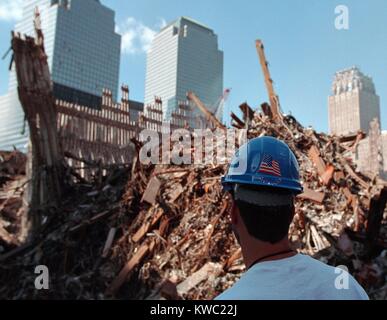 Worker at the 'pile' of rubble from the collapse of WTC 2, the South Tower on Oct. 3, 2001. The ruins of the Twin Towers formed 15 meters high piles. In the background are damaged but repairable buildings: L-R: World Financial Center 2 and 3, and the New York Telephone Building (Verizon Building). (BSLOC 2015 2 111) Stock Photo