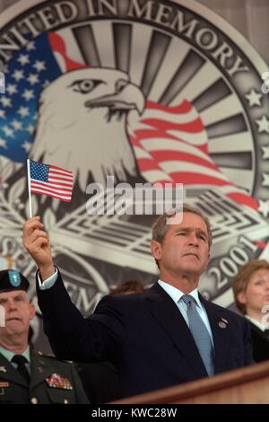 President George W. Bush at Remembrance Service for the 9-11 victims at the Pentagon. Behind Bush 43 is an elaborate backdrop with an eagle and he holds up a small American flag. Oct. 11, 2001, the one month anniversary of the 9-11 Terrorist Attacks. (BSLOC 2015 2 175) Stock Photo