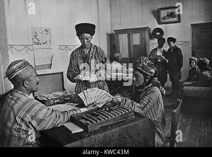 Turkmenian collective farmers receiving their share of yearly profits in the 1930s. The farm administrator calculates with an Abacus. Pictures of Stalin and Lenin hang on the walls. (BSLOC 2015 14 6) Stock Photo